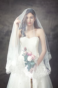 woman wearing white wedding gown holding bouquet of flowers