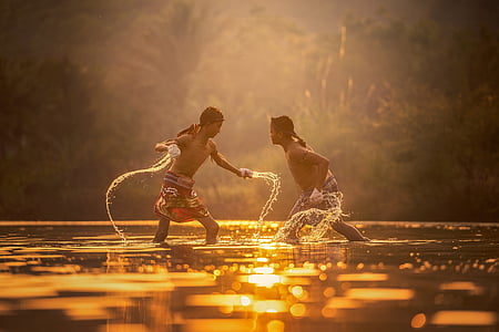 two men standing on body of water taken during sunset