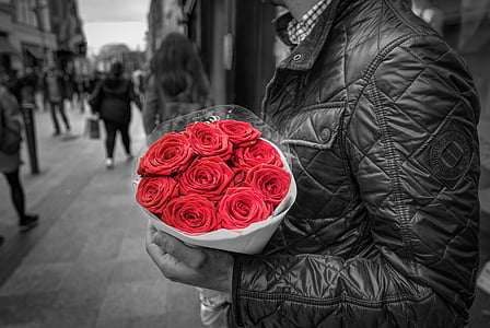 selective color photography of man holding bouquet of red roses