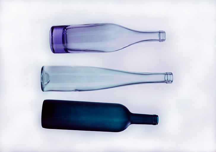 purple, black, and clear glass bottles with white background photo