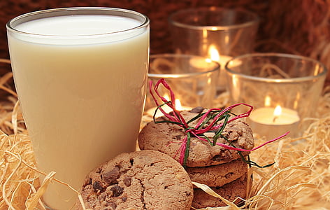 clear drinking glass filled with milk near candles