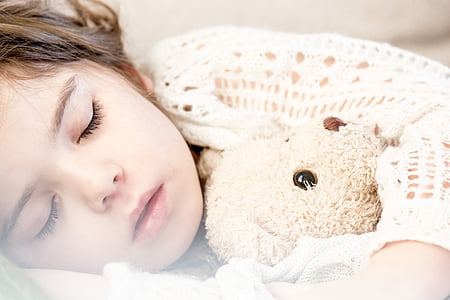girl sleeping beside grey teddy bear