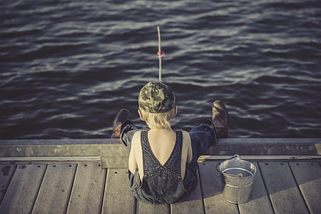 boy's wearing fishing wader sitting on the brown dock