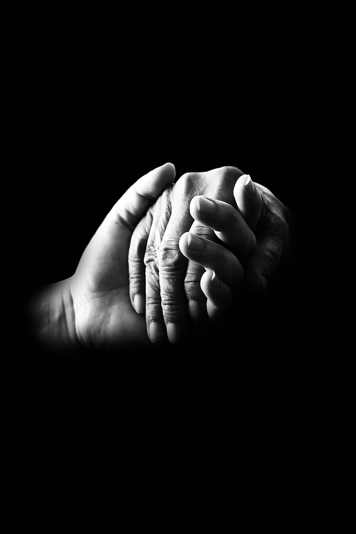 grayscale photo of two hands holding each other