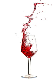 pouring of red wine in clear long stem wine glass