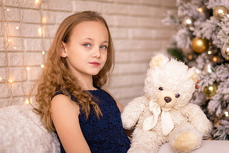 photo of girl sitting couch holding white bear plush toy