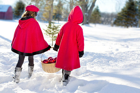 two toddler wearing red robe while walking on white snow covered ground