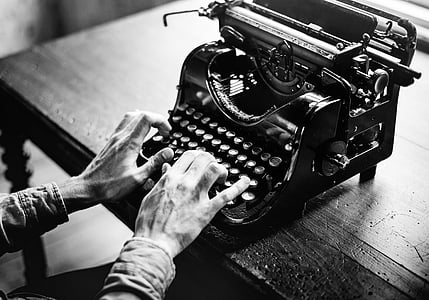 grayscale photo of person using typewriter
