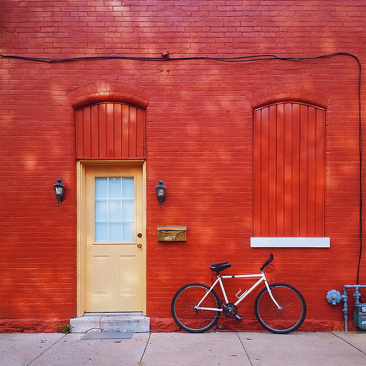white mountain bike parked beside red painted bricked wall