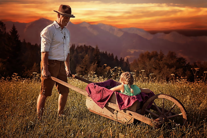 girl riding wooden wheelbarrow during sunset