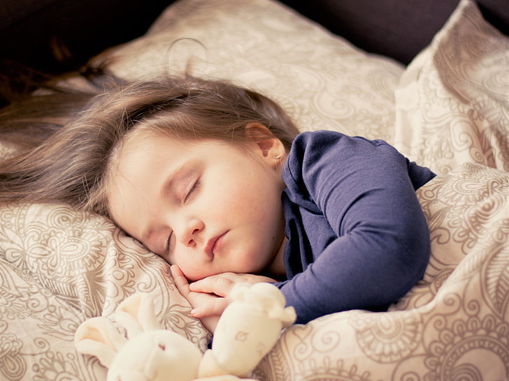 toddler wearing black long-sleeved shirt sleeping on brown bed comforter set