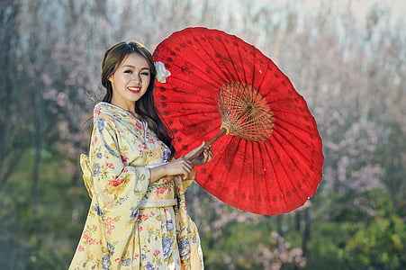woman in beige floral dress holding oil paper umbrella
