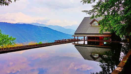 brown house on body of water and mountain at distance during daytime