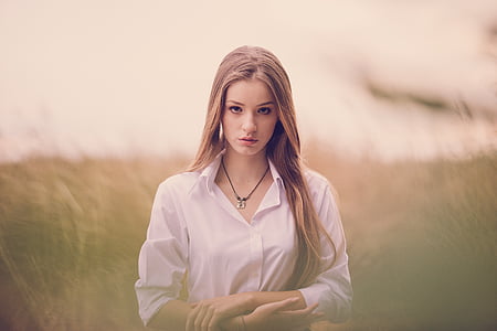 woman in white button-up collared long-sleeved shirt on grass field focus photography