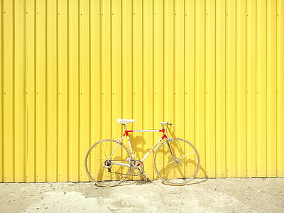 white and red road bike near yellow fence