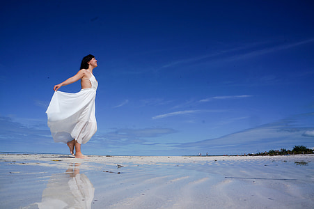 woman in white sleeveless dress on shore under blue sunny sky