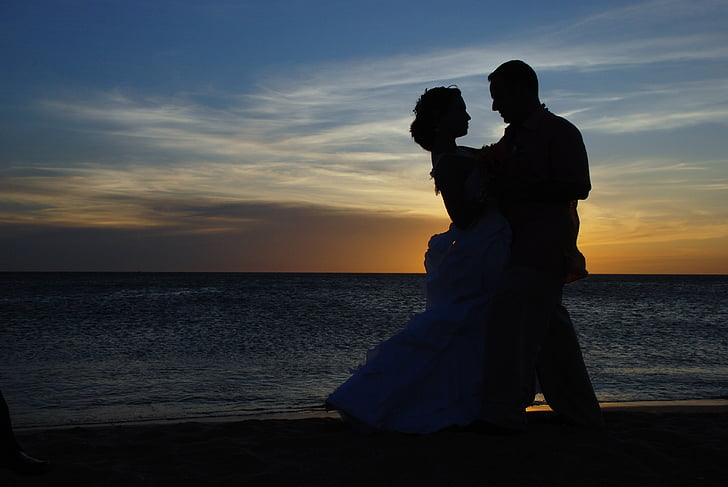 silhouette of dancing man and woman on shore during sunset