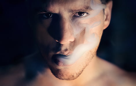 photo of man blowing smoke