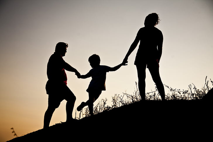 silhouette of family on hill during twilight