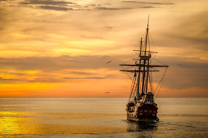 brown and black galleon ship on body of water at golden hour