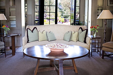 beige floral sofa in front of round brown wooden coffee table