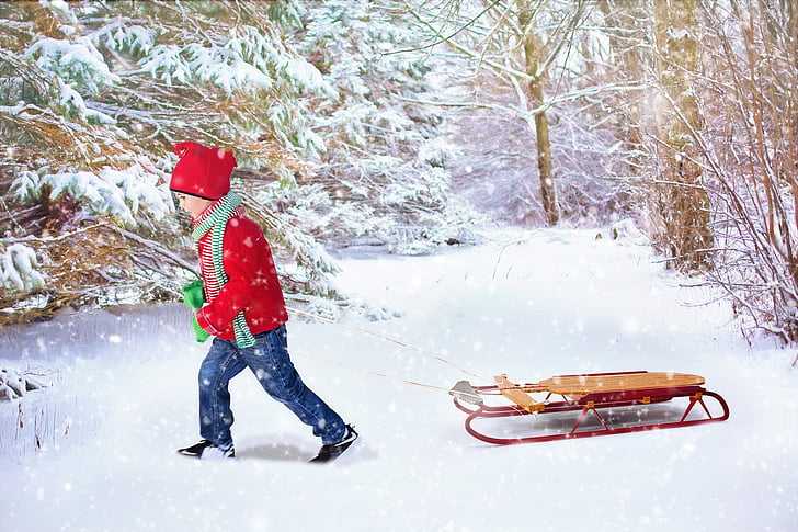 child in red long-sleeved winter top pulling brown and red snow sled