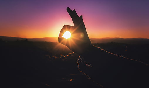 silhouette photo of okay hand sign through sunrise