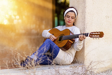 woman playing brown classical guitar