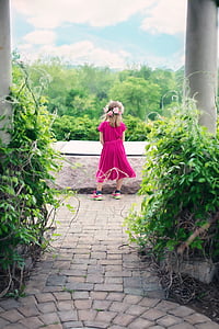 girl wearing pink sleeved dress standing on pathway