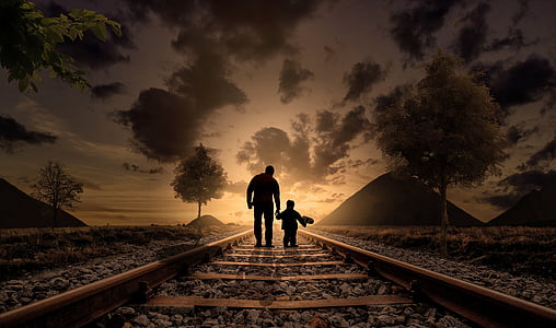 silhouette photo of two person walking on train rail during golden hour
