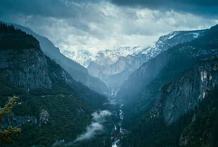 river between mountain range under gray clouds