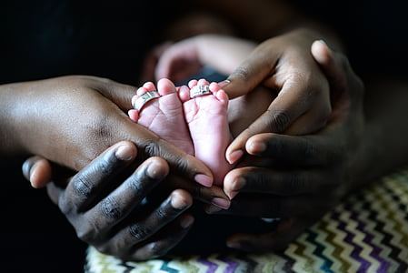 two adult hands with baby feet