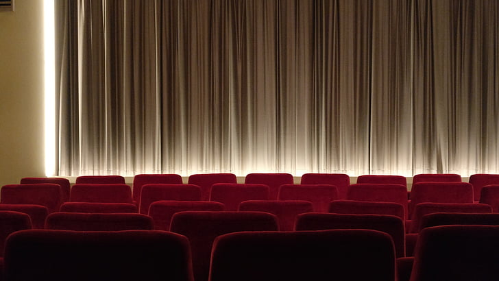 empty theater covered with brown curtain and red chairs