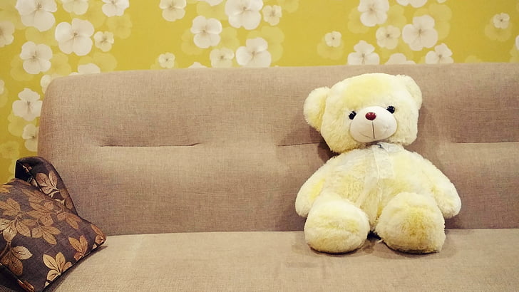 white bear plush toy on brown fabric sofa