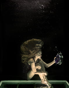 woman holding alarm clock while under the water photo