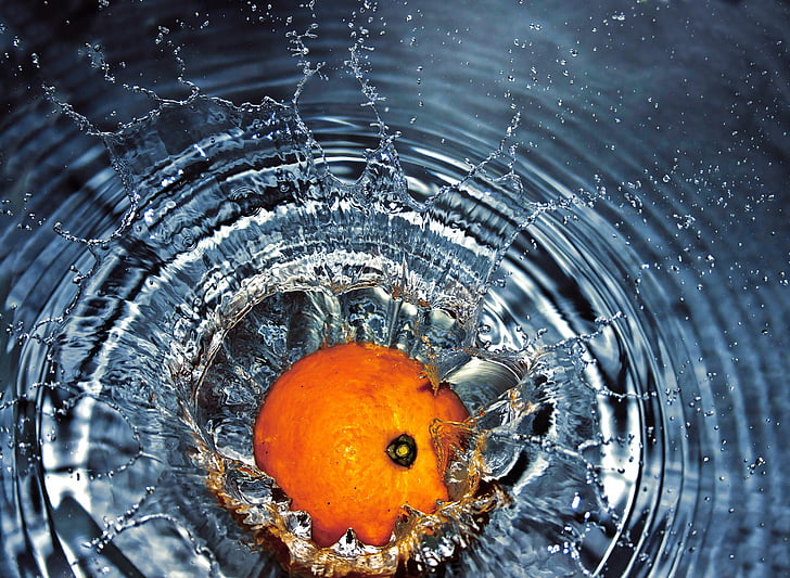 orange fruit drops on water