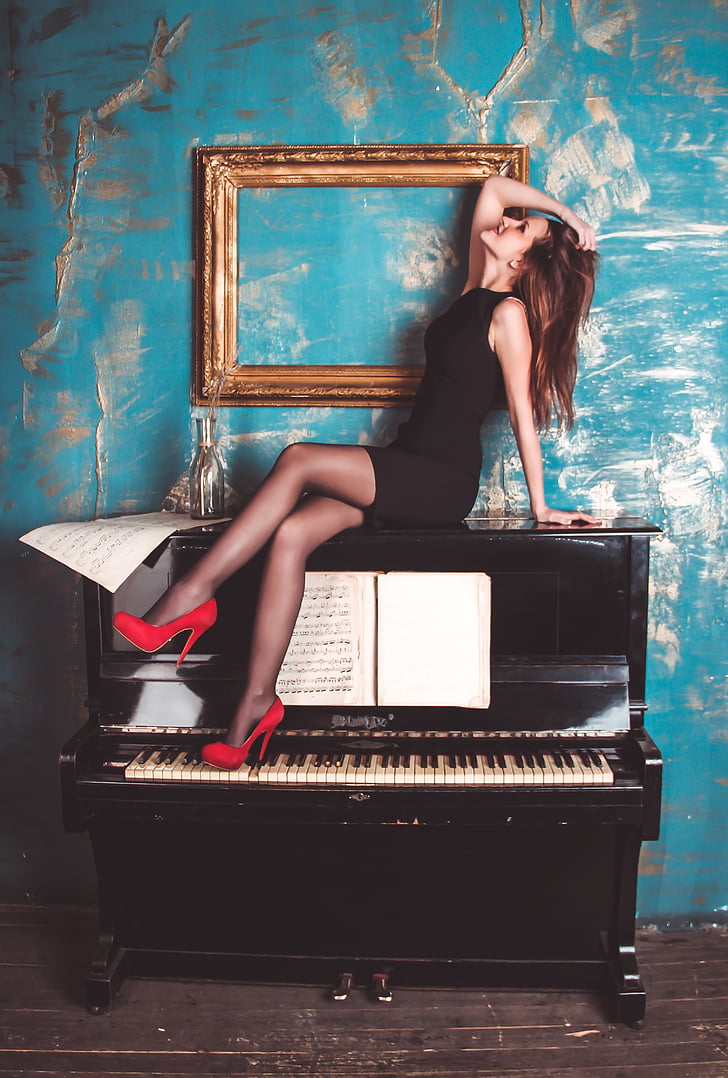 woman on top of black upright piano