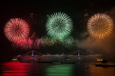 Fireworks under the bridge with boats on body of water