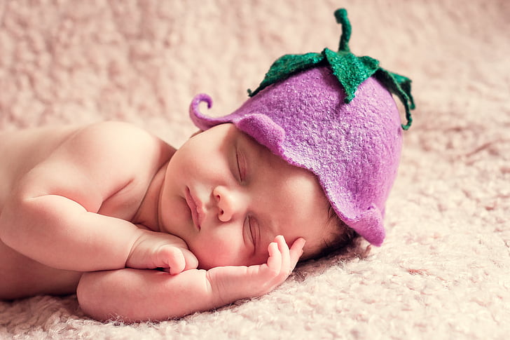 baby wearing egg-plant-themed hat