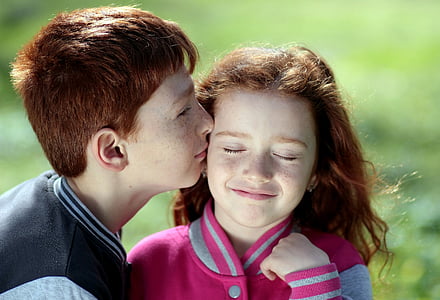 boy kissing girl in shallow focus photography