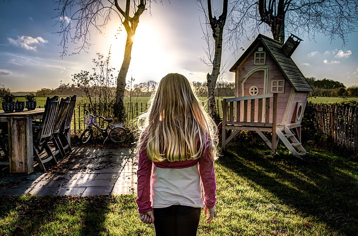 girl standing near wooden playhouse