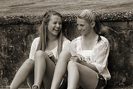 two girls sitting leaning at wall
