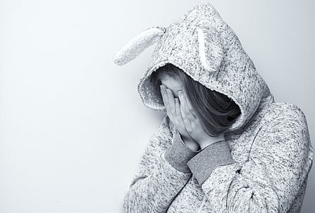 greyscale photo of woman wearing hoodie crying