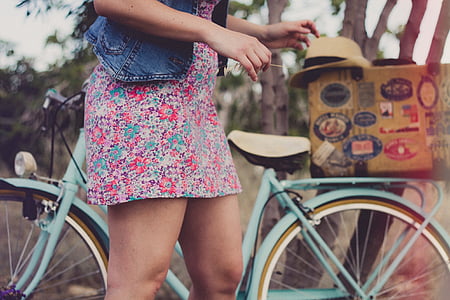 girl wearing multicolored floral mini dress standing beside green bicycle during daytime