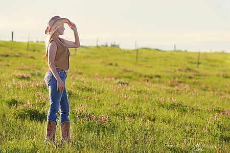 woman standing on grass field holding her hat during daytime
