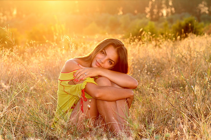 woman in yellow dress sitting on green grass during daytime