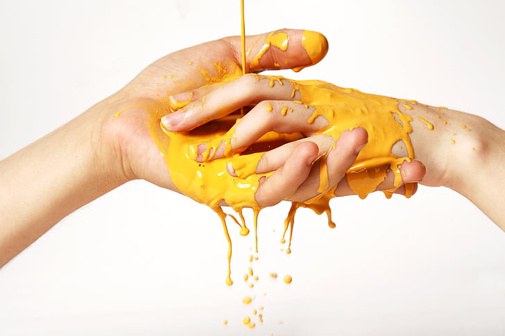 two person hands soaked in yellow liquid