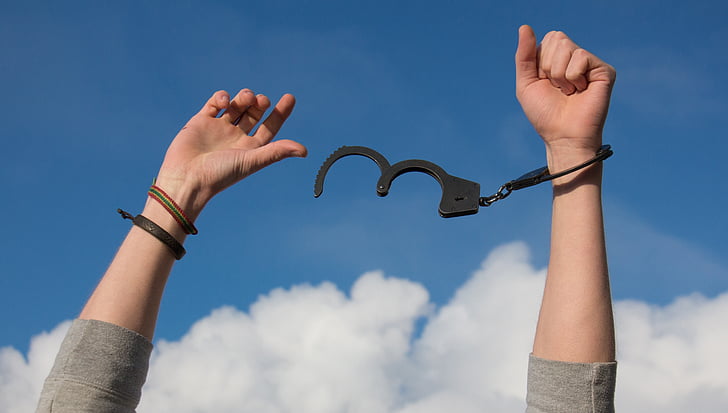 person freeing a handcuff with a view of blue sky