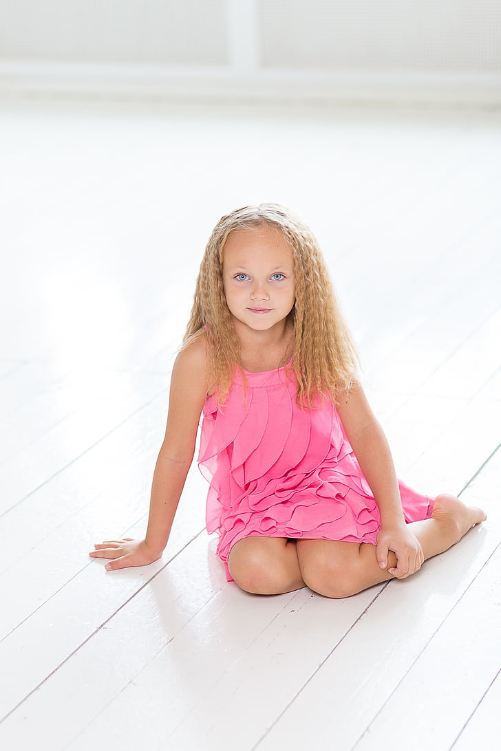 girl wearing pink dress sitting on the floor