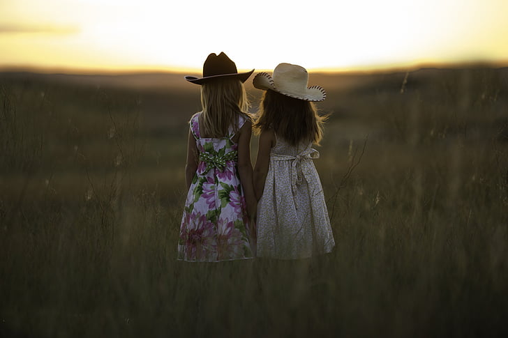 two girl wearing hats watching sunrise during daytime